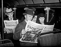 Bussresenärer läser tidningen Aftonbladet. Med rubriken Tjeckiska regeringen går: