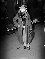 Författare Karen Blixen med rävboa och hatt på järnvägsstation.