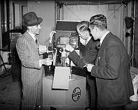 Tre män i kostym undersöker en Philips televisions kamera i samband med försök med televisionssändningar från en studio på Kungsgatan 48.
