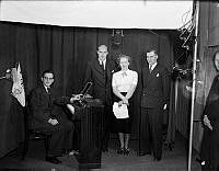I inspelningsstudion på Kungsgatan 48 i samband med försök med televisionssändningar. Siri Olson med manuskript i handen var Sveriges första televisionsspeaker.