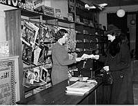 En kvinna köper Aftonbladet på Aftonbladets depeschkontor och resetjänst.