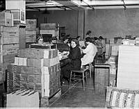 Kvinnor sitter och arbetar vid högar av motböcker. Bilden är tagen i samband med motbokssystemets 25-år jubileum år 1939.