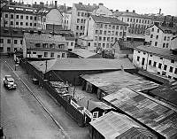 Brädgården på Rosenlundsgatan 5, kvarteret Skjutsgossen. Till höger Ekesiöö brädgård, S:t Paulsgatan 15, Husen i fonden är Krukmakarg. Till höger Torkel Knutssonsgatan.