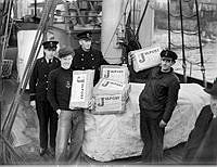 Fyra sjömän med julpostpaket på ett fartygsdäck.