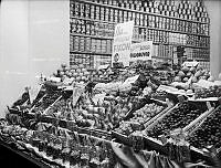 En stor frukt och grönsaksdisk med bland annat Spanska Gulddruvor, päron, hög och blomkål och fikon vid julen 1939. I bakgrunden uppradade konservburkar i hyllor.