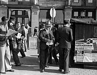 Krigsutbrottet. Människor framför en kiosk vid Central Palatset. Tegelbacken 2.  En man läser Aftonbladet med rubriken Krig mot Finland. Bilden ska vara tagen 1 september 1939.