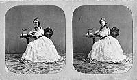 Porträttbild av operasångerskan Jenny Lind vid ett litet bord där det står en stereoskopapparat för att betrakta stereofotografier.