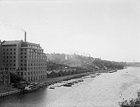 Kungsholms strand västerut från Sankt Eriksbron. 
Till vänster Choklad-Thules, eller AB Förenade Chokladfabrikernas, stora fabriksbyggnad. 
I fonden Stadshagen där Vattentornet skymtar.