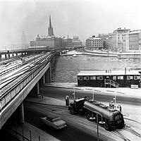 Vy från Slussen längs tunnelbanebron mot Mälartorget och Riddarholmen. I förgrunden tankbil vid bensinpumpar på Sjöbergsplan samt byggbaracker.