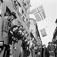 Fredsdagen den 7:e maj 1945. 
Flaggviftande människor firar freden längs Mäster Samuelsgatan.