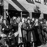 Fredsdagen den 7:e maj 1945. Glada människor viftar med flaggor framför Mäster Samuelsgatan 18.