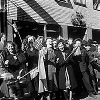 Fredsdagen den 7:e maj 1945. Glada människor viftar med flaggor framför Mäster Samuelsgatan 18.