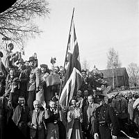 Fredsdagen den 7:e maj 1945 i Stockholm. 
Glada och flaggviftande människor firar freden.