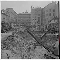 Klarabergsgatan österut/Drottninggatan i fonden med Husmoderns varuhus (Drottninggatan 46). Tunnelbanebygge.