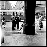 Strövtågsbilder från 1950-talets Stockholm. Folk utanför NK:s entré på Hamngatan. Rakt fram Västra Trädgårdsgatan och en buss. Sidenhuset till höger.