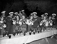 Män från Marinberedskapen firar midsommar på Skeppsholmen tillsammans med folkdräktsklädda flickor..