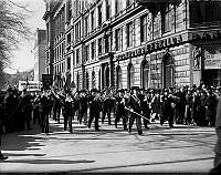 Demonstrationståg på första maj med musikår och åskådare. Stockholms enskilda bank på Karlavägen 45 i bakgrunden.