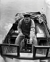 Gustaf Hjerzell vevar sig med handkraft fram i en motorbåt.