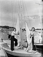Två kvinnor hissar segel vid Sandhamns regattan.