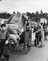 Oktoberflyttningarna. Flyttningssöndag. Människor med dragkärror lastade med möbler går Drottningholmsvägen österut. I fonden till vänster Finsens väg.