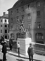 Del av skulpturen S:t Göran och draken på Köpmantorget, prinsessan. I bakgrunden kvarteren Marsyas och Diana.