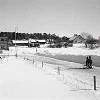 Vy från sydväst mot Anneboda gård längs Sylvestergatan med kälkåkande barn. Till vänster skymtar radhuset vid Sylvestergatan 12.