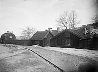 Trähusbebyggelse i Vita bergen. I bakgrunden till vänster uppförs ett hus i kvarteret Persikan/Papayan tillhörande Stockholms bomullsspinneri. 