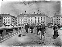 Norrbro och Gustaf Adolfs torg med ryttarstatyn.
Folk flanerar.

