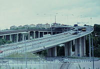 Vy söderut från Ringvägen med Johanneshovsbron som är under byggnad. I fonden Skanstullsbron och bostadshus runt Gullmarsplan. Till höger skymtar Skanskvarn.