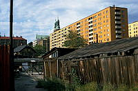 Skjul och äldre trähus i kv. Geväret. Vy mot Hornsgatan och flerbostadshuslänga vid Drakenbergsgatan. I fonden Högalidskyrkans torn.