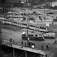 Vy mot nordost över Södermalmstorg med spårvagnar, bussar, bilar och trafikanter. I fonden pågår anläggningsarbete vid Söder Mälarstrand.