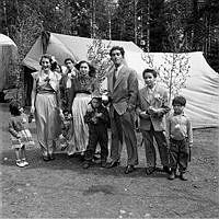 Män, kvinnor och barn framför ett tält vid ett romskt bröllop.
