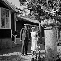 Reportage från Sandhamn under sandhamnsregattan 1941. En man och en kvinna står framför sitt solur och sitt hus.