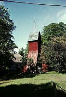 Haninge. Dalarö. Rödmålad klockstapel sedd med Dalarö kyrka t.v.