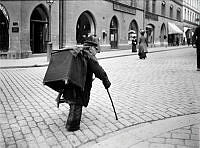 Gatumusikant med käpp går på en gata i Stockholm.