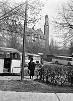 Dam som väntar på bussen vid Jarlaplan. I bakgrunden kvarteret Skatan och Engelbrektskyrkan i kvarteret Korsnäbben.  
