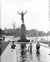 Barn leker med båtar i spegeldammen vid Strömparterren, Norrbro. Carl Milles bronsstaty 