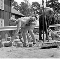 Gatuarbetare i Sommarhettan. Den kvinnliga stensättaren Göta Falk jobbar på Öregrundsgatan.