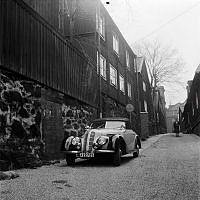 Från ett reportage om förhållandena i Djurgårdsstaden. 
En bil parkerad på Östra Varvsgatan. I fonden Nordenskiöldsgatan.