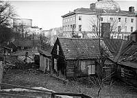 Gamla kåkar vid Saltmätargatans förlängning. Detta är den sista resten av bondesamhället i Stockholm. Nuvarande Observatorielundens parklek.
I fonden Stadsbiblioteket och Handelshögskolan. 
