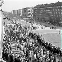 Demonstrationståg på väg österut på Valhallavägen mot Gärdet. Första maj demonstration på gammal och beprövat sätt med musikkår, standar, fanor, paroller och åskådare.