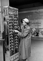 En kvinna köper strumpor i Bredenbergs nya strumpautomat på Drottningatan 54 C.