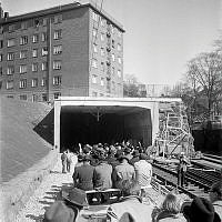 En ny järnvägsförbindelse invigs. Dressiner med träbänkar på väg in i tunneln framför Högbergsgatan 59.