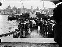 Kistor med kvarlevorna efter Salomon August Andrée, Nils Strindberg och Knut Fraenkel från Andréexpeditionen förs i land på Skeppsholmen från M/S Svensksund.