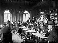Interiörbild med gäster från Rydbergs bar tagen i samband med att baren stängdes den 30 september 1914.
Bland gästerna finns operasångaren Oscar Bergström sittande som tredje person från höger.