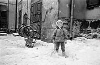 Norra Smedjegatan 5. Ett litet barn leker i snön på bakgården.