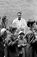 Norra Smedjegatan 24, blomsterhögtid i Sankta Eugeniakyrkan. Kyrkoherde Peter Hornung står bakom barnen.
