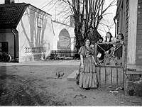 Grupporträtt med kvinna och fyra barn på trappan utanför hus vid Lilla Tanto. I fonden syns Årstabron
