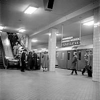 Tunnelbanestationen Kungsgatan, numera Hötorget. Ett tunnelbanetåg står inne och folk är på väg upp med rulltrappan.