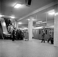 Tunnelbanestationen Kungsgatan, numera Hötorget. Ett tunnelbanetåg står inne och folk är på väg upp med rulltrappan.